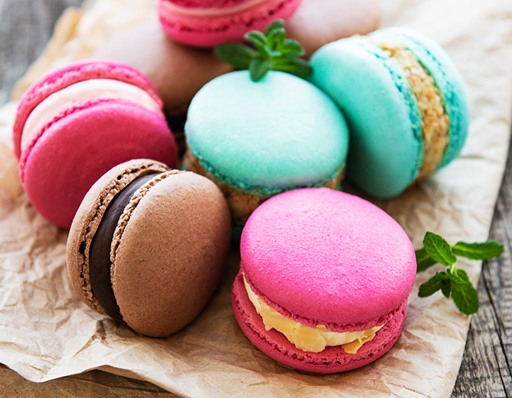 Colorful macaroons and mint on old wooden background
