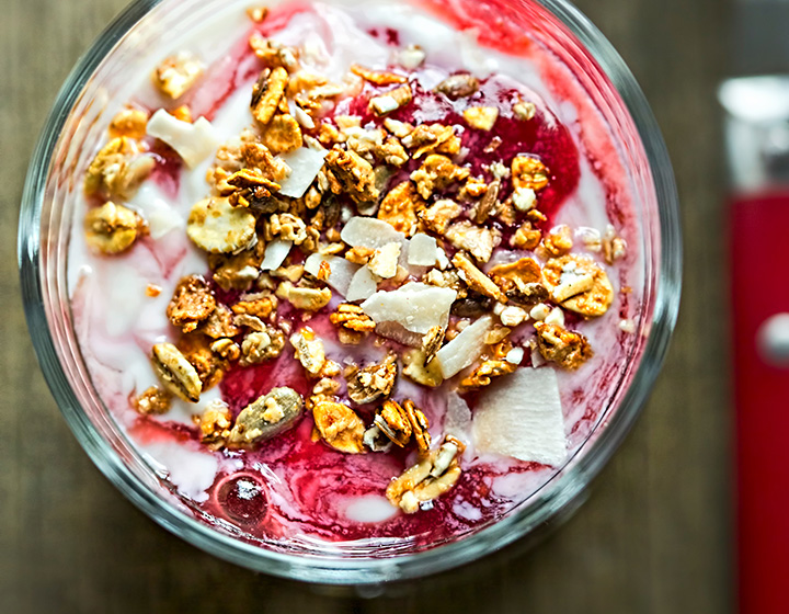 Bowl of red fruit and granola on a yoghurt