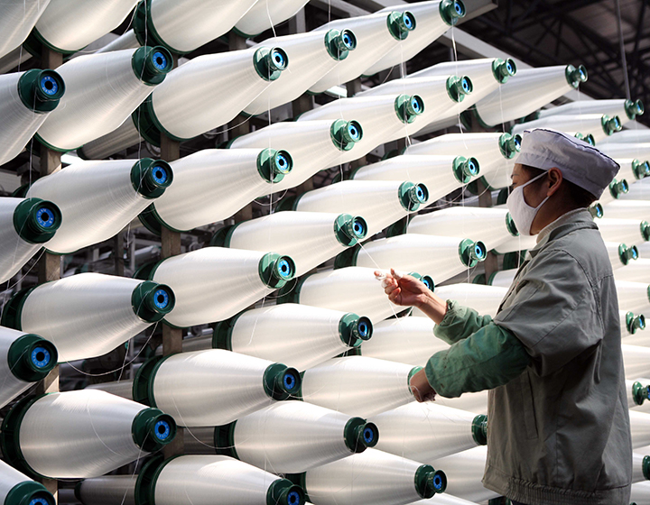 Reels of white glass fibre with a person unwinding one