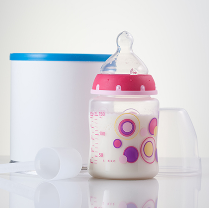 A tub of infant milk formula and a pink baby bottle
