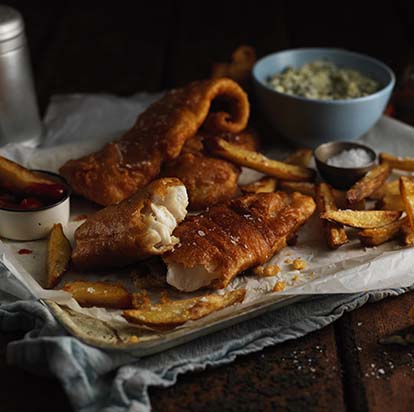 Fried fish and chips on a tray with tartar sauce