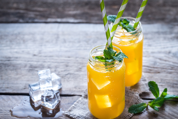 Glass jars of orange juice with ice