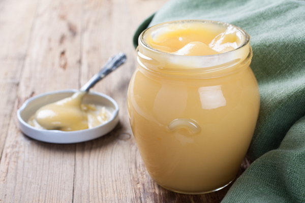 Jar of homemade lime curd with a spoon on old wooden background. Selective focus