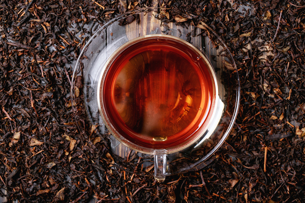 Black tea in glass cup over a dark wooden background. Top view. Copy Space