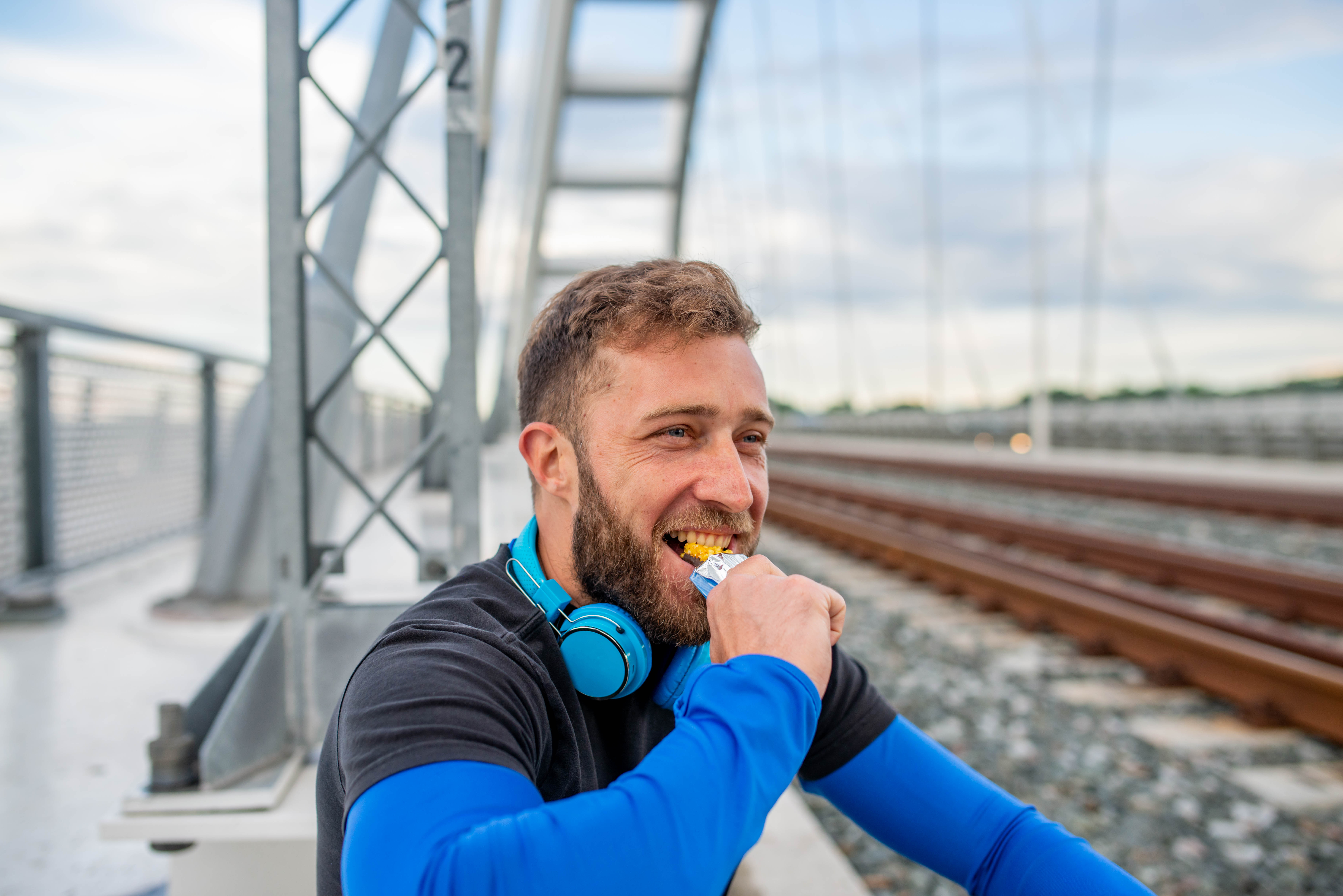 A smiling athlete with a beard eating a bar of chocolate after training