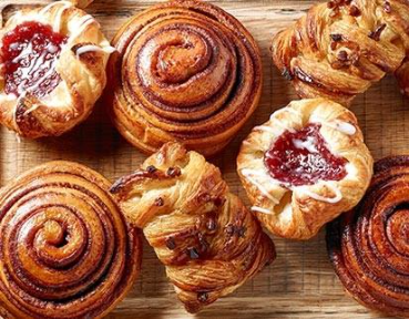 Assorted colorful iced drinks in glass cups arranged outdoors with sunlight highlighting green, red, and orange beverages