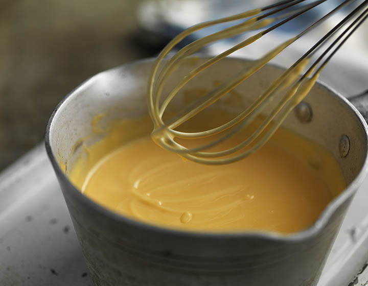Custard in a saucepan with whisk