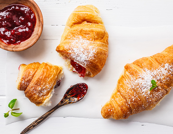 Two croissants with icing sugar and jam