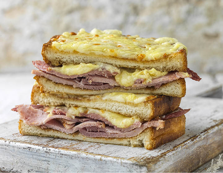 Cheese and ham toastie, cut in half and on top of a wooden board