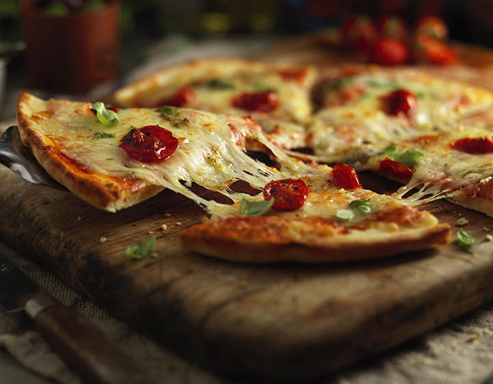 Slice of cheese and tomato pizza being lifted