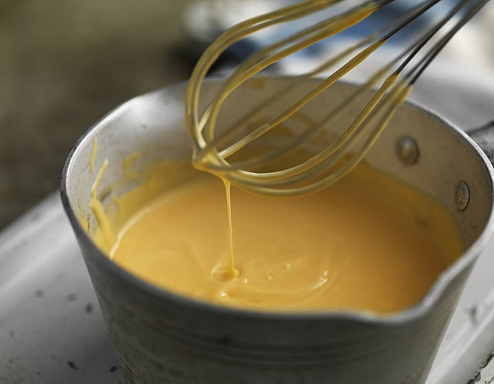 Pan of custard with a dripping whisk raised above it