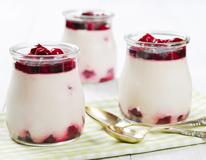 Jars of white and red fruit parfait with silver spoons