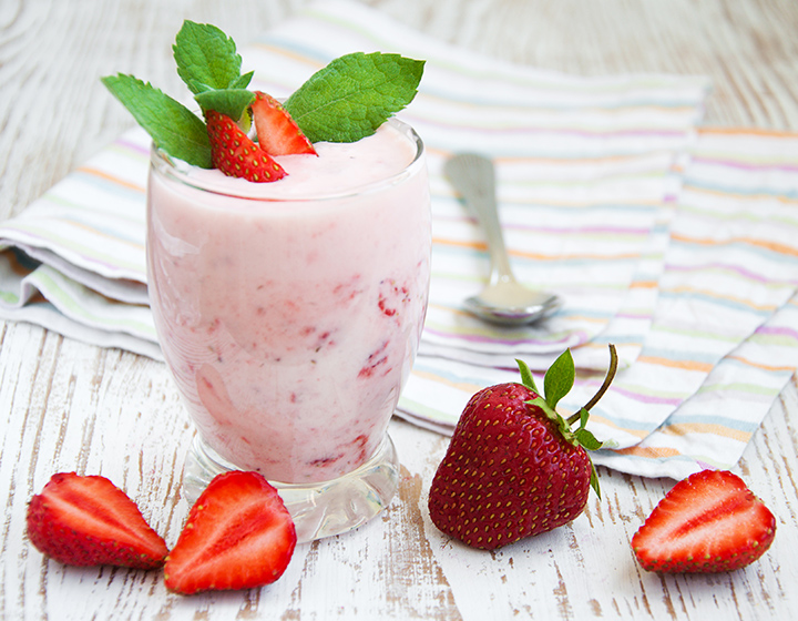 Glass of pink yoghurt with strawberries and a spoon