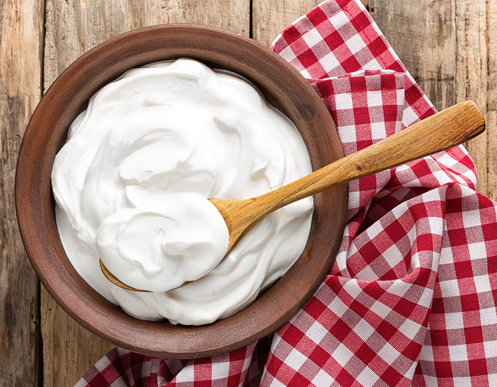 Large bowl of white yoghurt with a wooden spoon