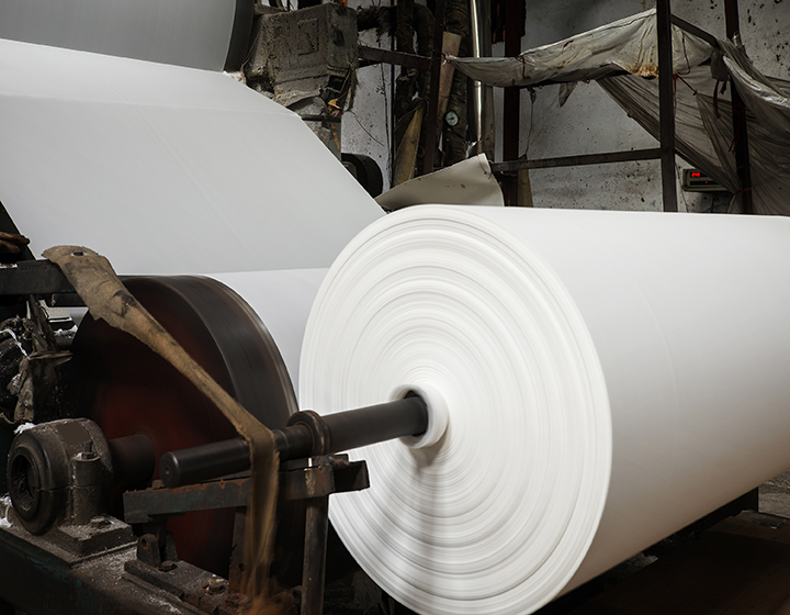 A large roll of white paper being unfurled from a machine