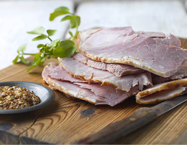 Slices of ham on a chopping board with a knife