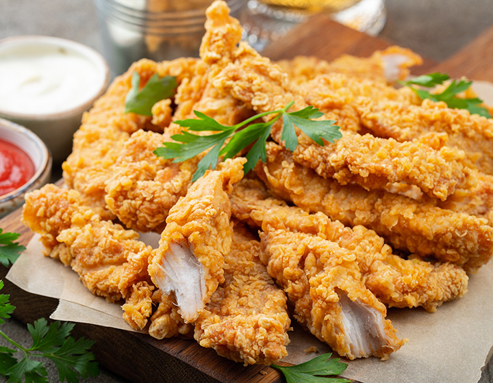 Fried strips of chicken with a garnish and tomato sauce