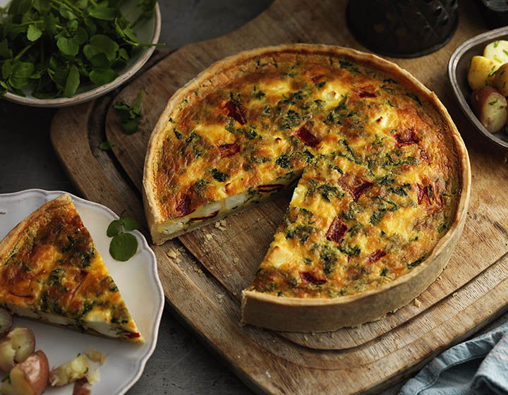 A quiche on a board with a slice cut out