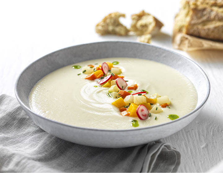 A grey bowl of white celeriac soup