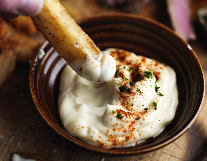 Dipping a chip into a bowl of mayonnaise with paprika