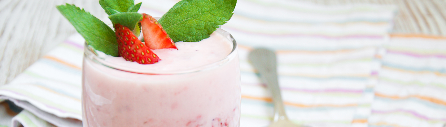 Pink fruit yoghurt in a glass with a strawberry and mint