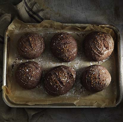 Brown gluten free bread rolls on a baking tray