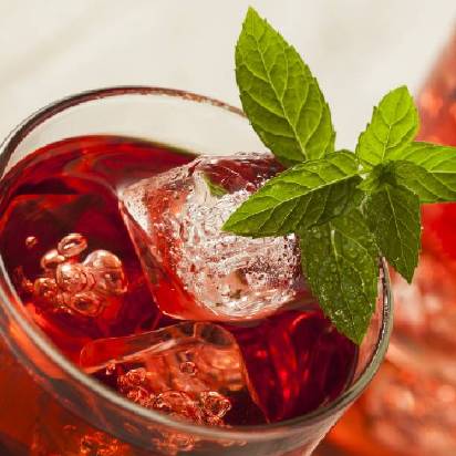 Close-up of a glass of red soft drink with ice and garnished with mint