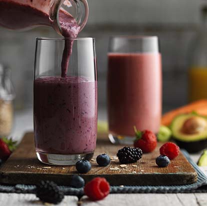 Raspberry, blackberry and blueberry smoothie being poured into a glass