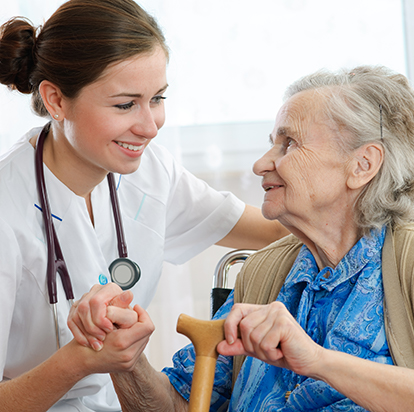 Nurse in white holding the hand of an elderly woman