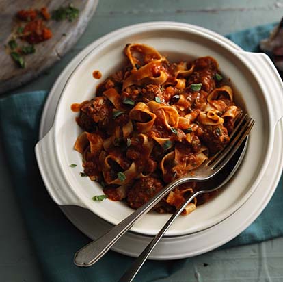 A bowl of spaghetti bolognese with fork and spoon