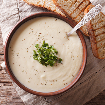 Top down view of a bowl of creamy soup with sliced toasted bread