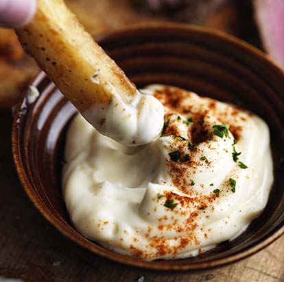 Dipping a skin-on chip into creamy mayonnaise sprinkled with cayenne