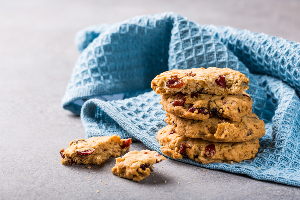 Oat meal cookies with raisins and cranberries on light gray background and blue napkin. Health breakfast or snack concept