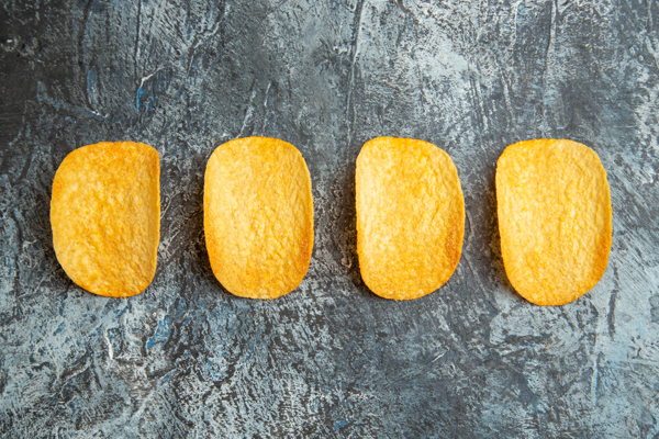 Horizontal view of crunchy baked chips lined up in a row on gray background