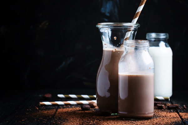 Cocoa or milk with chocolate, glass bottles, changing background, selective focus