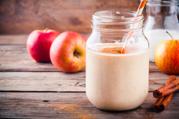 Healthy breakfast: smoothies with red apple and cinnamon in a glass mason jar on a wooden background