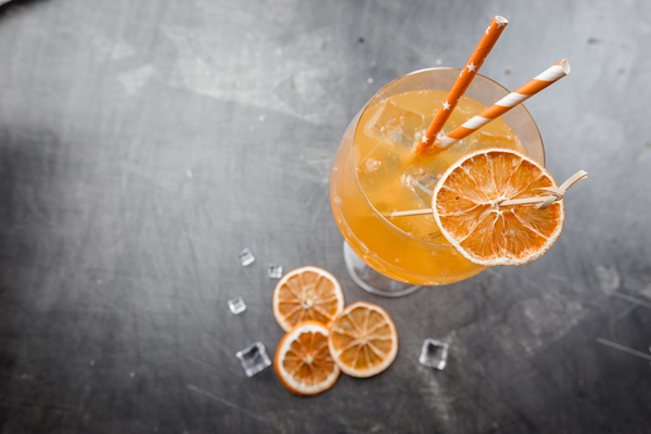 Glass of aperol soda cocktail with ice cubes over dark background, top view