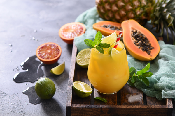 Fresh cold drink cocktail or lemonade with tropical fruits, papaya, pineapple, lime, juicy summer beverage