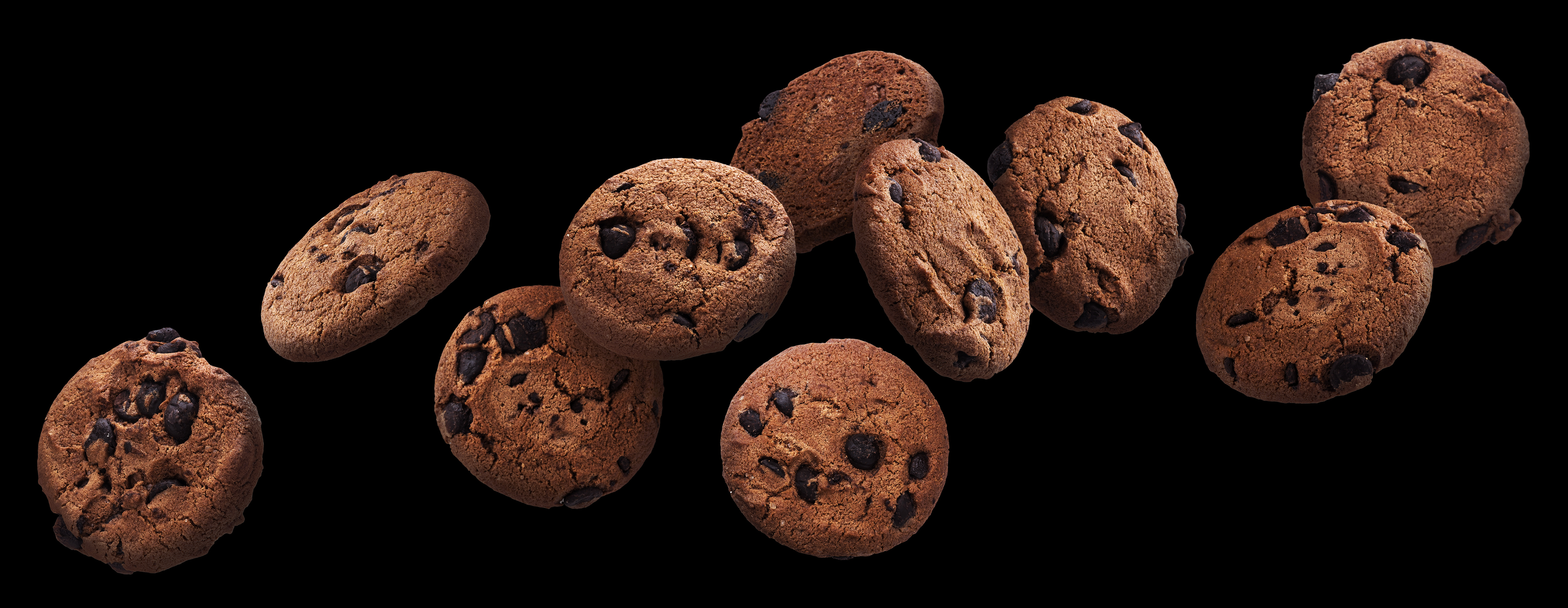 Chocolate chip cookies falling over black background, flying biscuits