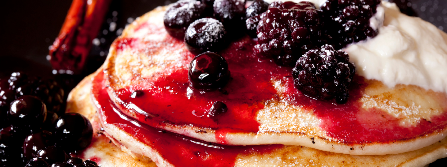 Pancakes topped with a compote of blackberries and blueberries, and yogurt.