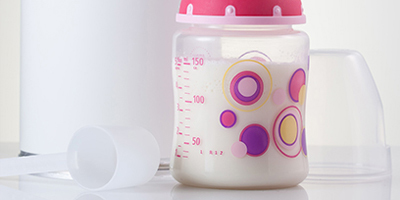 A tub of infant milk formula and a pink baby bottle