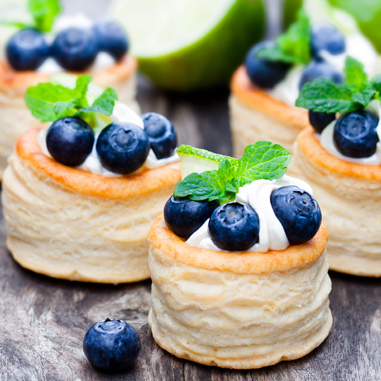 Round bakery snacks with cream, blueberries, and mint leaves on top, representing co-texturizers.