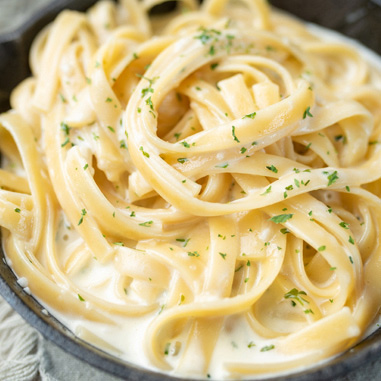 Fettuccini alfredo in a bowl with parsley on top showing the savory texturizer application
