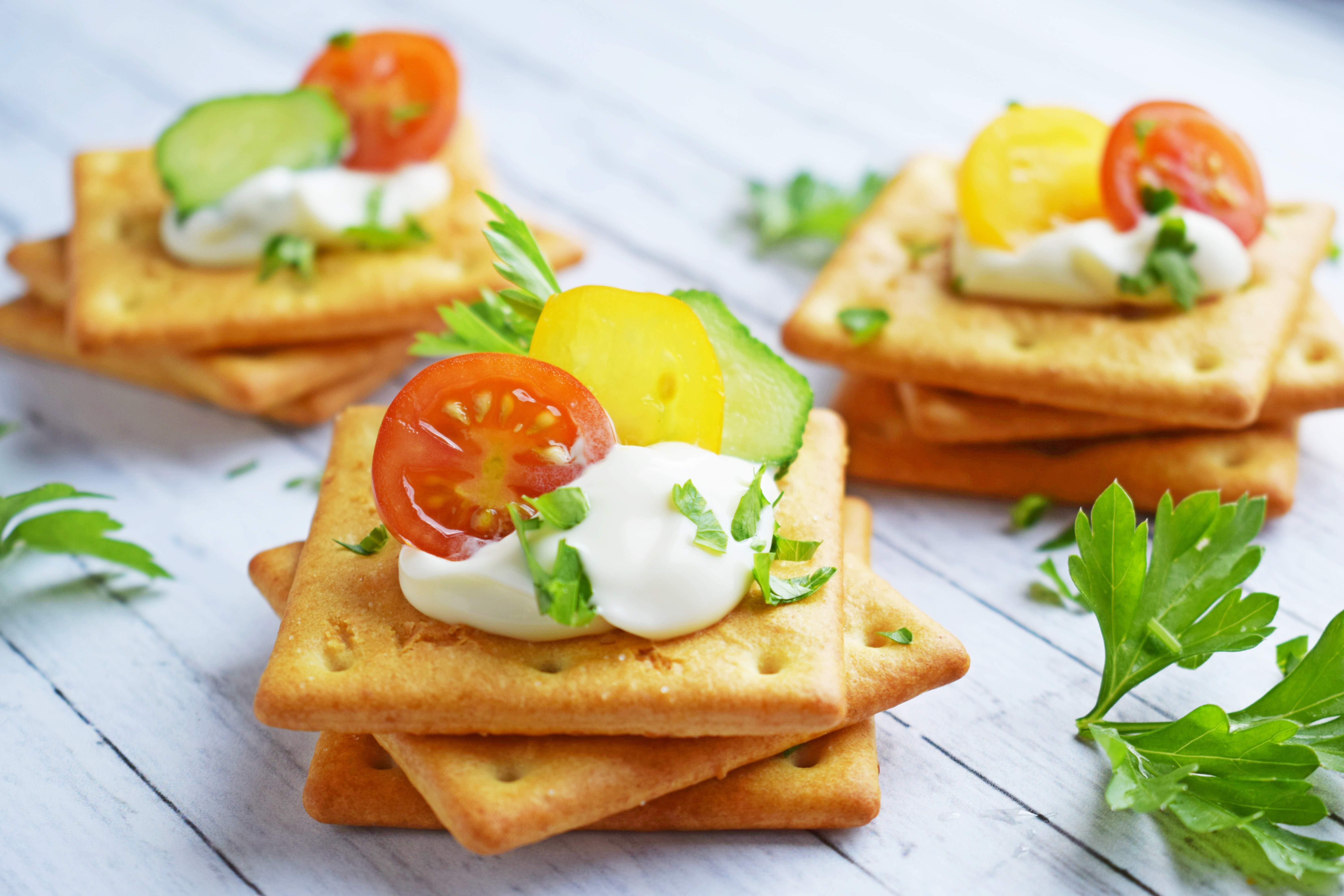 Delicious crackers with cheese sauce and vegetables.Snack on wooden background.