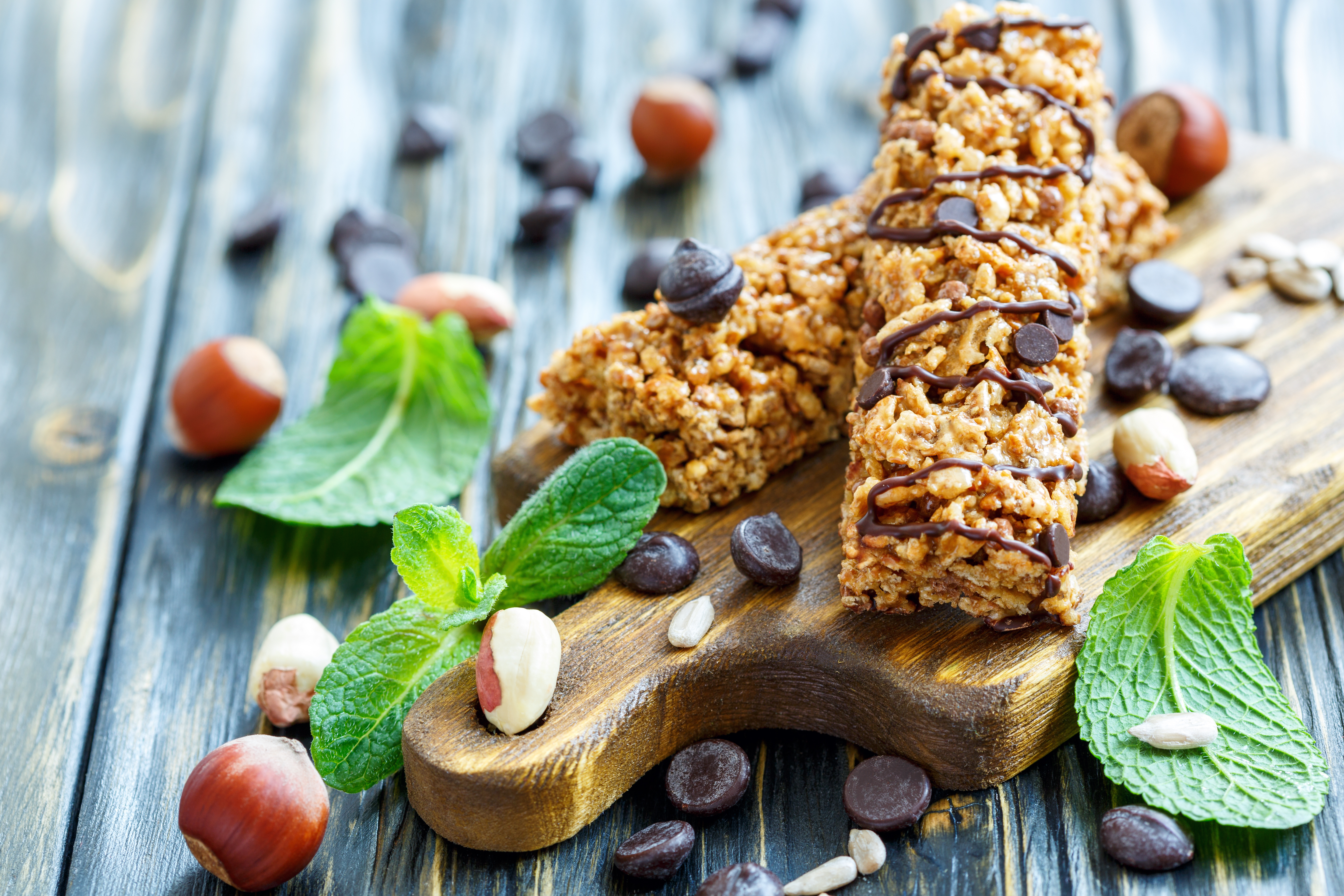 Cereal bars with nuts and chocolate on old wooden table, selective focus.