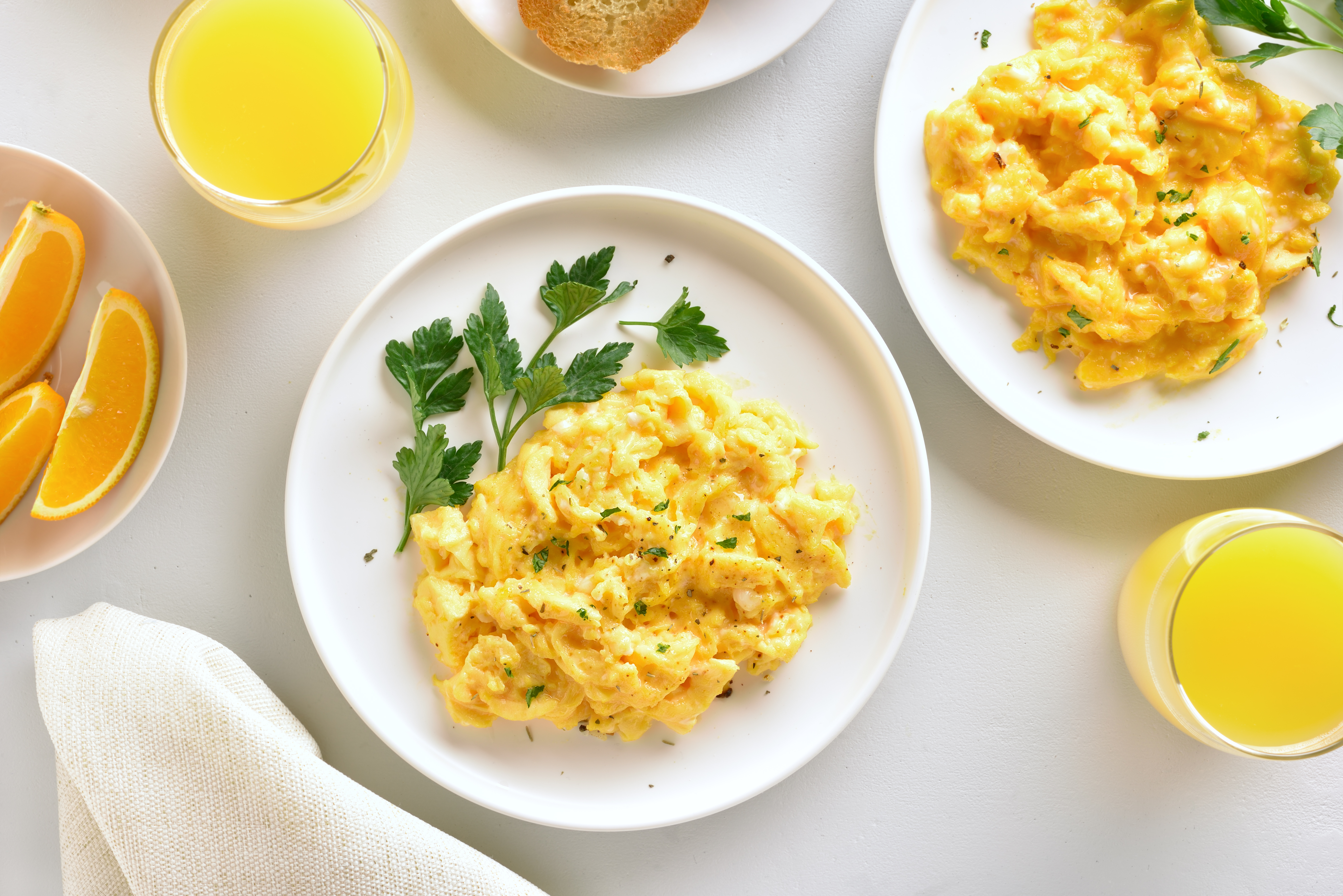 Healthy diet breakfast concept. Scrambled eggs and orange juice over white stone background. Top view, flat lay