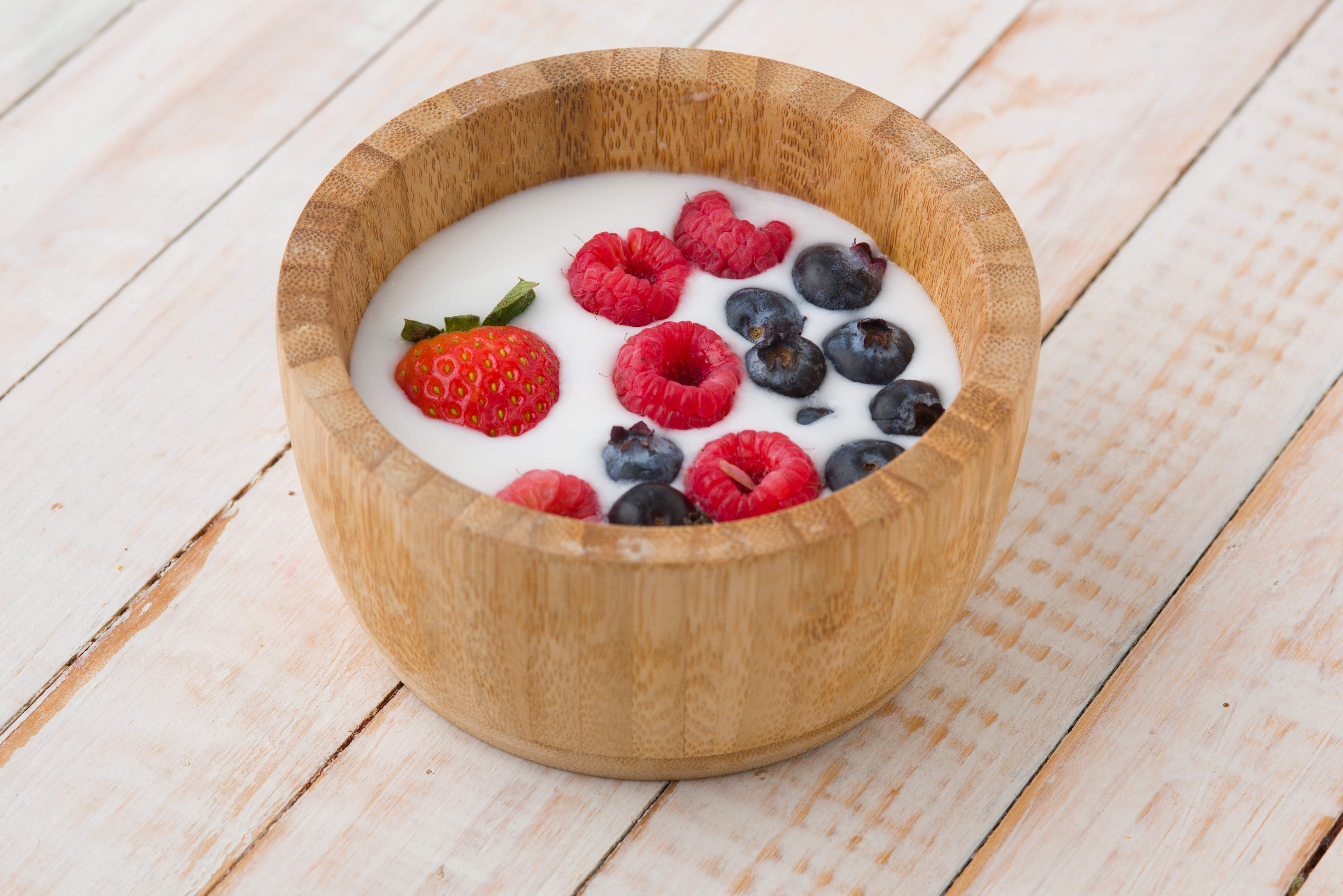 Vegan yogurth with berries on a rustic wooden bowl