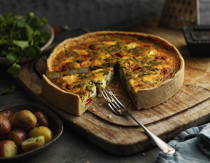 A quiche with a fork and a slice missing