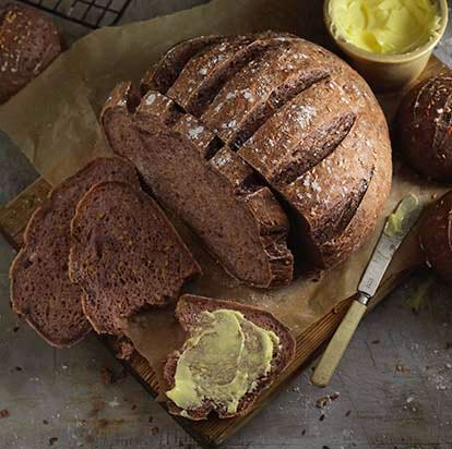 A dark gluten free bread loaf cut into slices