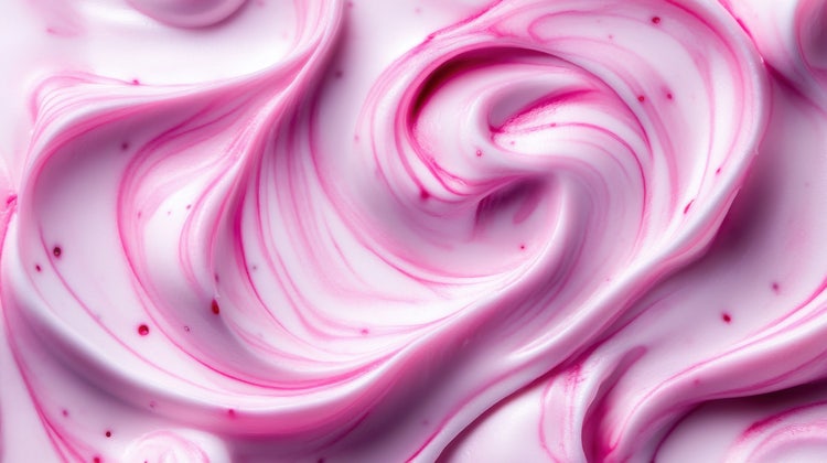 Close-up of smooth pink and white cream swirls with a glossy texture, resembling berry yogurt or whipped dessert